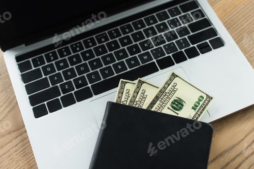Preview: top view of notebook with dollar banknotes on laptop with blank screen, anti-corruption concept