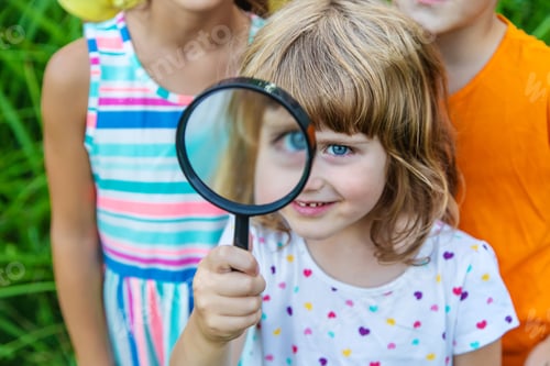 Preview: Children look at a magnifying glass on the nature. Selective focus.