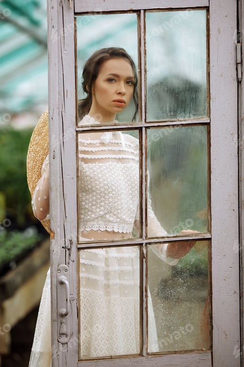 Preview: Beautiful young girl in a hat in a greenhouse