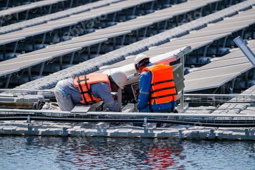 Preview: Two Asian workers are doing setup the photovoltaic panels floating on the water surface.