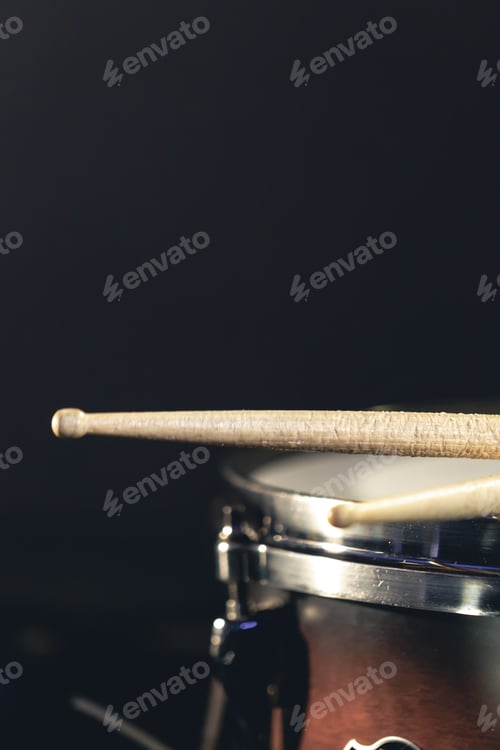 Preview: Close-up, snare drum and drumsticks on a dark background.
