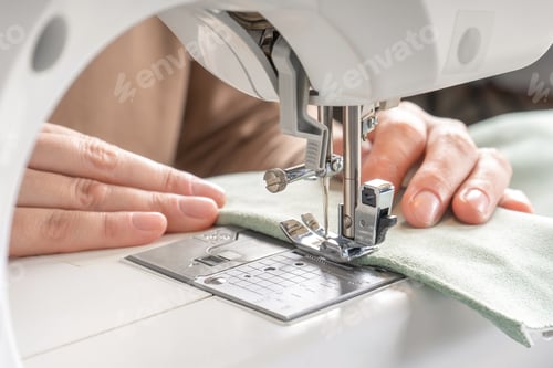 Preview: Female Hands Stitching White Fabric On Modern Sewing Machine At Workplace In Atelier