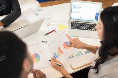 Preview: Businesswoman pointing at pie charts at conference table meeting