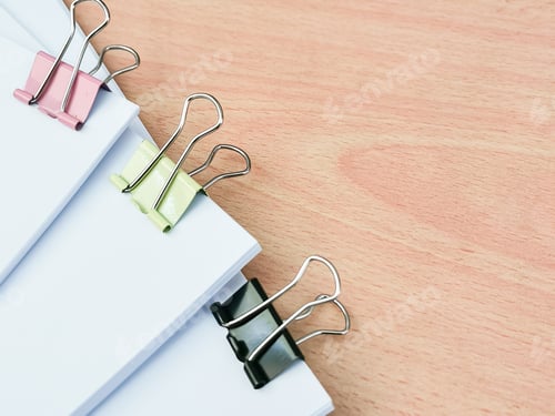 Preview: Image of binder clips with blank white paper on wooden table.
