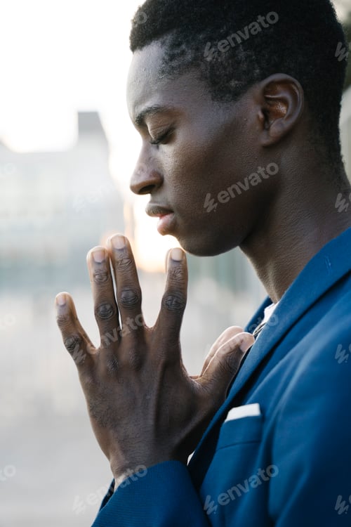 Preview: Businessman praying with hands together and eyes closed