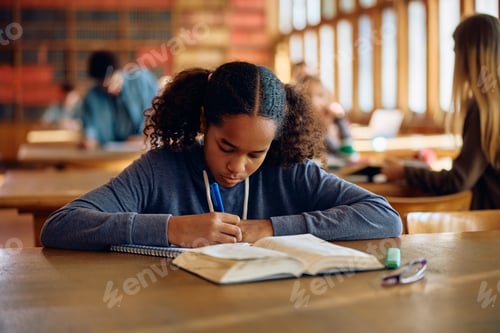 Preview: Black teenage girl writing during a class at high school.