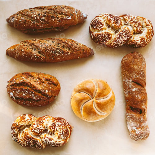 Preview: Variety of breads and pastries on baking paper. Top view.