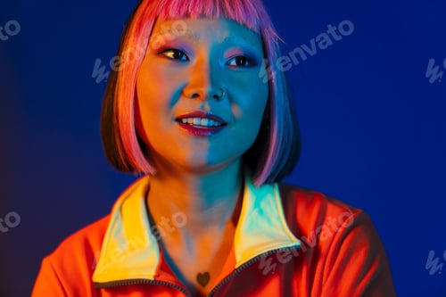 Preview: Asian girl with pink hair and piercing smiling while looking aside
