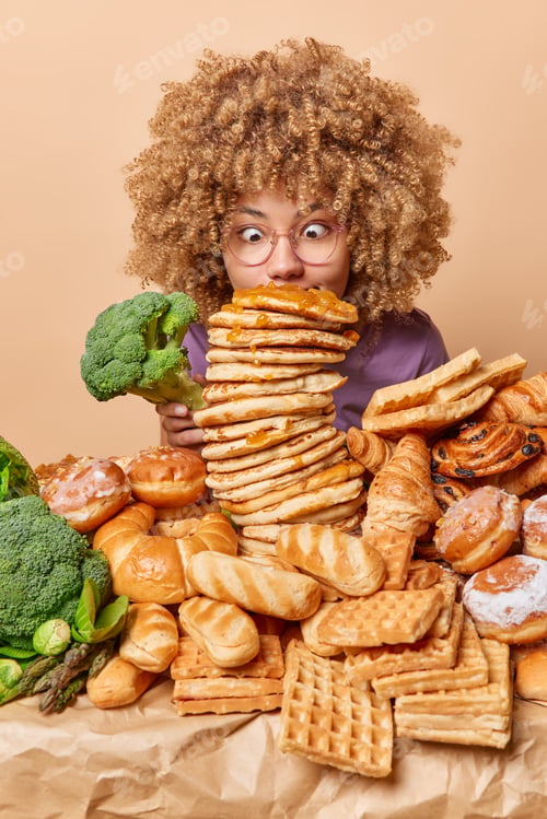Preview: Vertical shot of amazed woman stares at stack of delicious pancakes with jam holds green cabbage