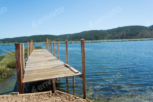 Preview: Picture of a wooden bridge on a shining lake against foliage mountains