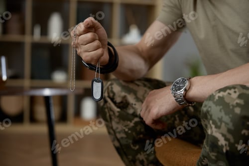 Preview: Closeup military person holding fighter dog tag badge in hand