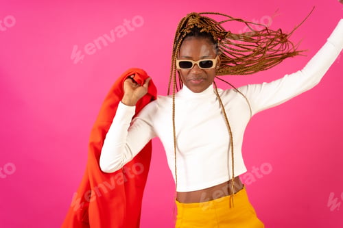 Preview: Black ethnic woman with braids on a pink background, wearing a red suit and white t-shirt dancing