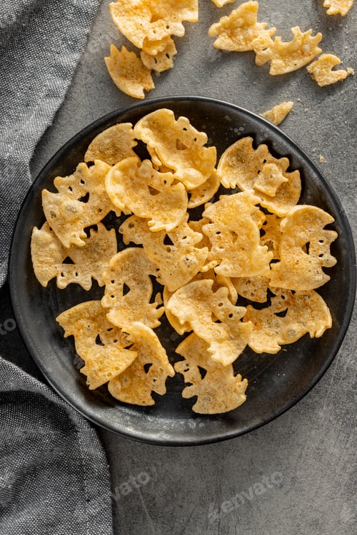 Preview: Halloween crispy bat shaped chips on plate. Top view.