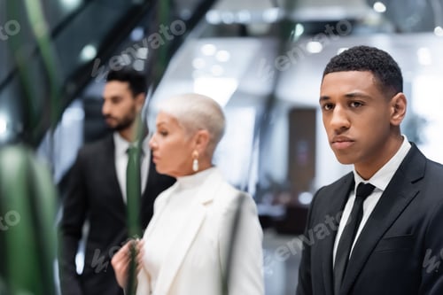 Preview: selective focus of african american security man near blurred businesswoman with bi-racial bodyguard