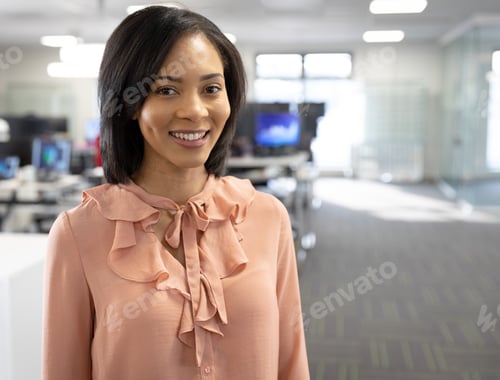 Preview: Smiling professional woman in office wearing pink blouse, standing confidently