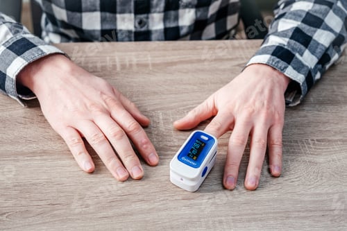 Preview: A man checking oxygen level at home with home oximeter