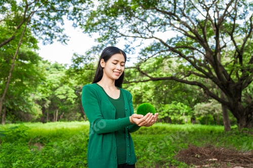 Preview: Forest conservationist holds small globe in hands,symbolizing global responsibility for protecting