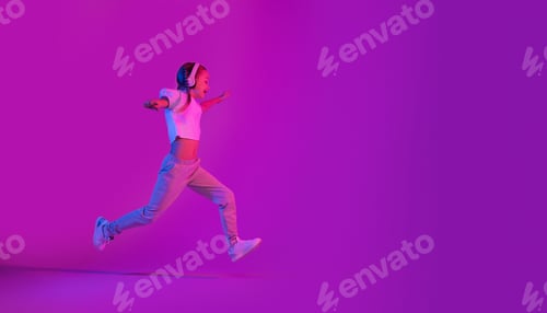 Preview: Preteen girl running towards copy space, using headphones