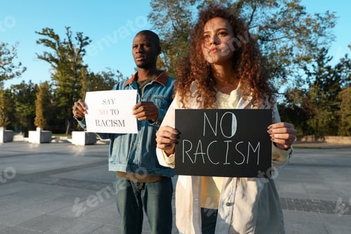 Preview: African American woman and man holding signs with phrase Say No To Racism outdoors