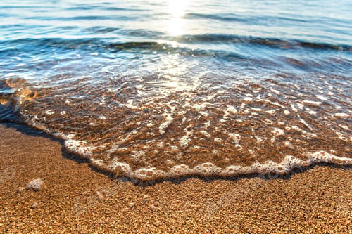 Preview: Close up of small sea waves with clear blue water over yellow sand beach at summer sunny shore.