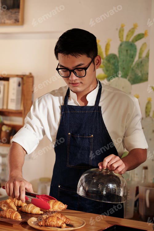 Preview: Waiter Putting Fresh Croissants on Plate