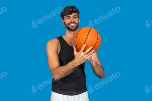 Preview: Basketball player holding ball smiling on blue background