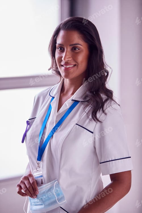 Preview: Portrait Of Female Mature Nurse In Uniform Holding Face Mask In Hospital