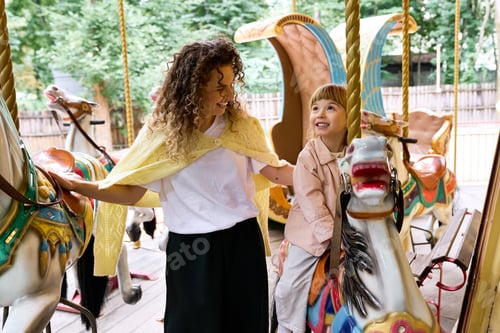 Preview: Joyful moments between mother and daughter at a colorful amusement park carousel