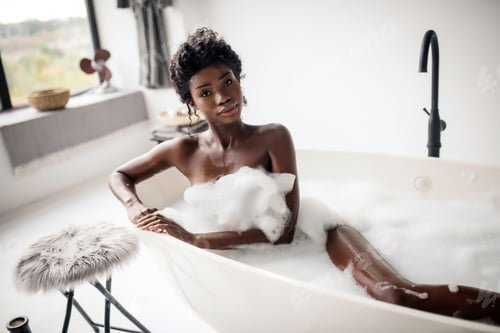 Preview: Beautiful dark-eyed woman lying in bath with foam
