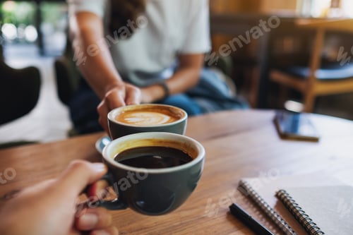 Preview: Closeup image of a man and a woman clinking white coffee mugs in cafe