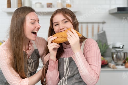 Preview: Happy mother and teen daughter cooking in the kitchen together.