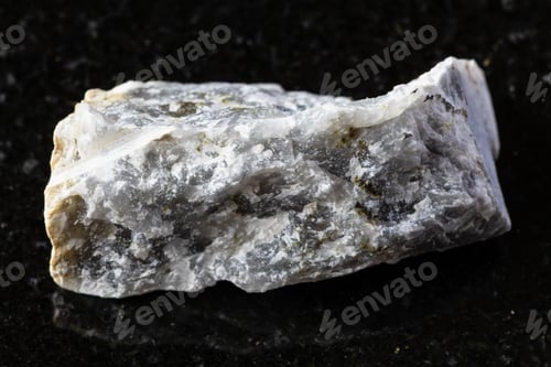 Preview: sample of raw melilite rock on black granite