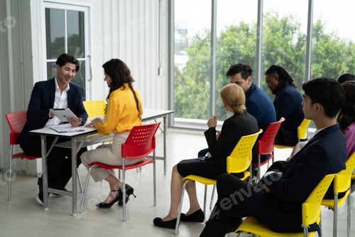 Preview: A group of people are sitting in chairs in a room, some of them are wearing suits. Job interview.