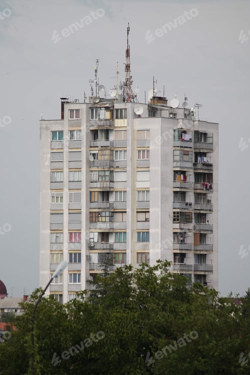 Preview: Vertical shot of a white residential building with balconies and ma antennas on the roof