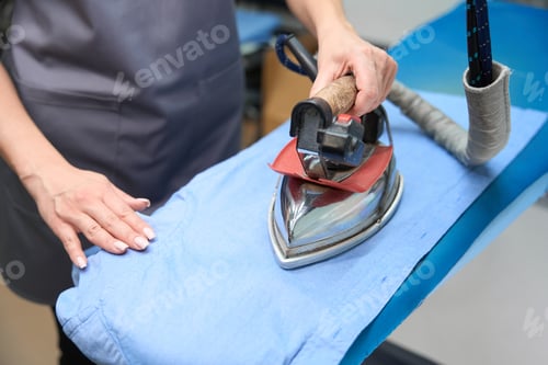 Preview: Woman using hot iron to remove wrinkles from shirt