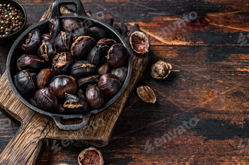 Preview: Roasted chestnuts served in a pan on a wooden cutting board. Wooden background. Top view. Copy space