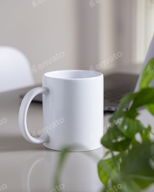 Preview: White coffee mug on grey office table against laptop, glasses and plant closeup, mockup