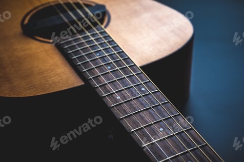 Preview: Acoustic guitar, music instrument resting against a dark black background with copy space