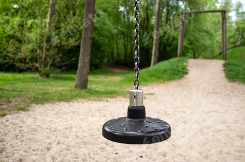 Preview: Children swing or zipline, with a round plastic seat attached to a metal chain, on the playground.