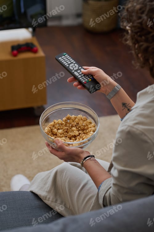 Preview: Woman watching TV with popcorn at home