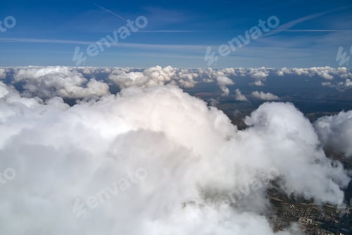 Preview: Aerial view from airplane window at high altitude of earth covered with white puffy clouds.