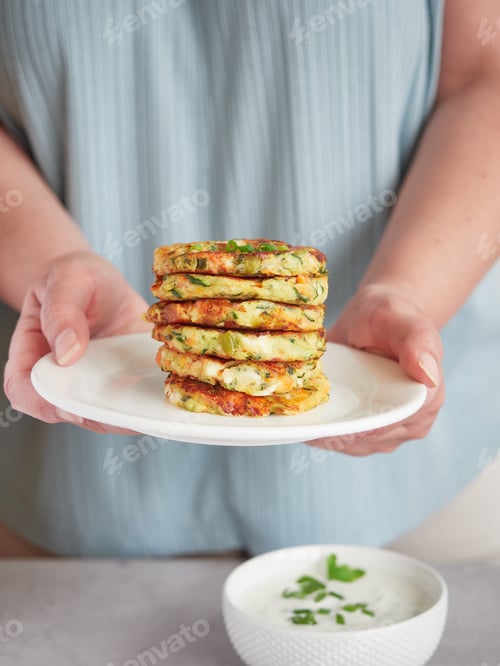 Preview: Stack of Zucchini Fritters Held by a Woman