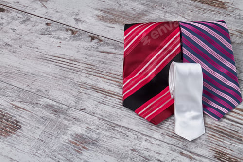 Preview: Colored rolled-up ties on white table.