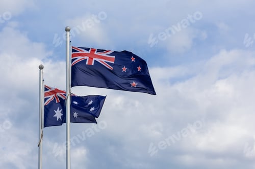 Preview: New Zealand and Australia national flags flying side by side against blue sky background