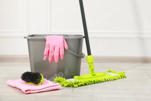 Preview: Microfiber mop, brush, bucket and gloves on wooden floor near white wall