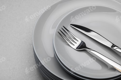 Preview: Stack of grey ceramic plates with fork and knife.