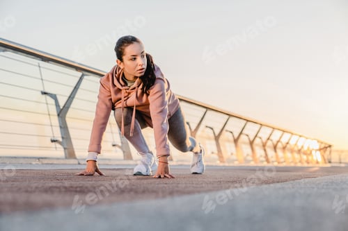 Preview: Sporty girl is preparing for jogging on the bridge with sunlight behind