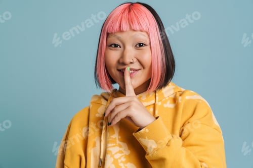 Preview: Asian girl with pink hair and piercing showing silence gesture