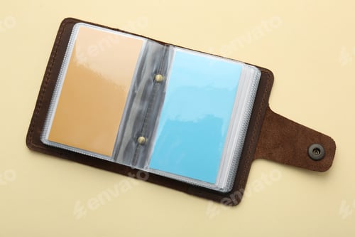 Preview: Leather business card holder with colorful cards on beige background, top view