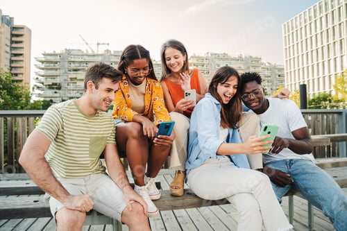 Preview: Group of teenagers smiling while watching and enjoying some funny videos next to the university